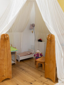 Kinderzimmer aus Holz mit einem weißen Stoffhimmel
